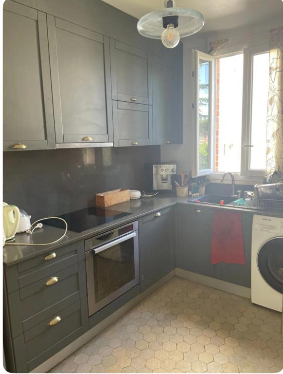 La cuisine est équipée de placards gris, d'un évier et d'un lave-vaisselle. dans l'établissement Chambre calme et lumineuse, à Paris