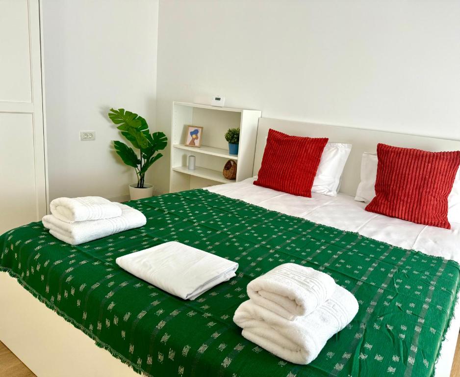 - un lit vert et blanc avec des oreillers rouges dans l'établissement Sky Residence Airport Therme Otopeni 5, à Otopeni