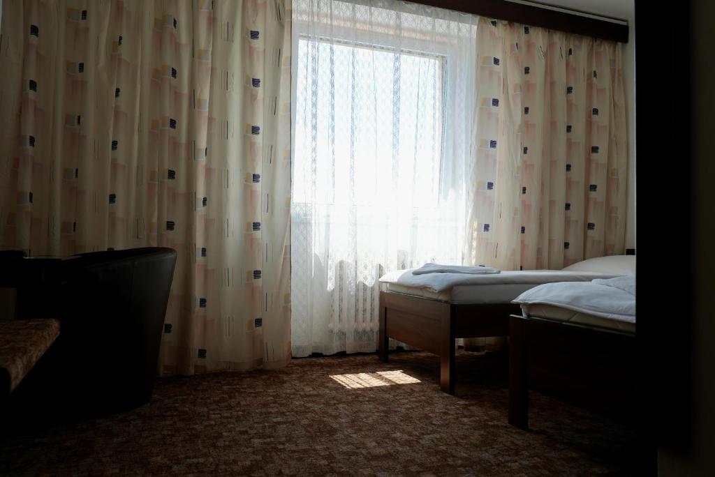 a bedroom with two beds and a window with curtains at Hotel Merkur - Jablonec nad Nisou in Jablonec nad Nisou