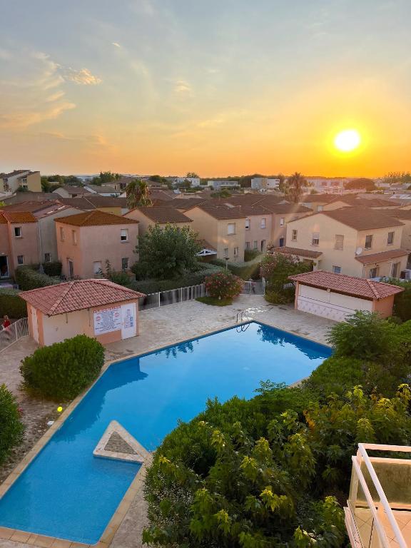 - une piscine dans une cour avec un coucher de soleil en arrière-plan dans l'établissement Maison Familiale dans le Domaine de la Plage avec Piscine Privée, à 200m de la Mer, à Valras-Plage