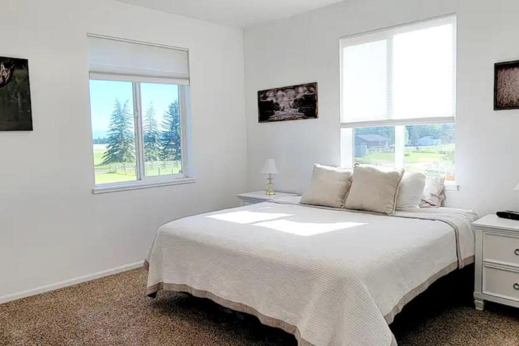 Un dormitorio blanco con una cama y dos ventanas. en Charming Chalet Close to GNP, Downtown & Game Room!, en Columbia Falls