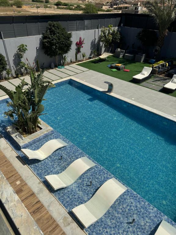 a swimming pool with white chairs in a building at Maria La Rosa By Seahorse in Al Baḩḩāth
