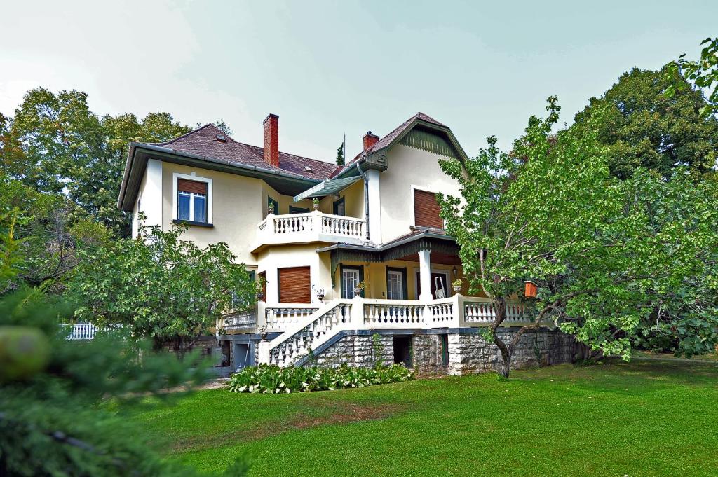 a large white house with a porch and a yard at Ambrózia Villa in Balatonfüred