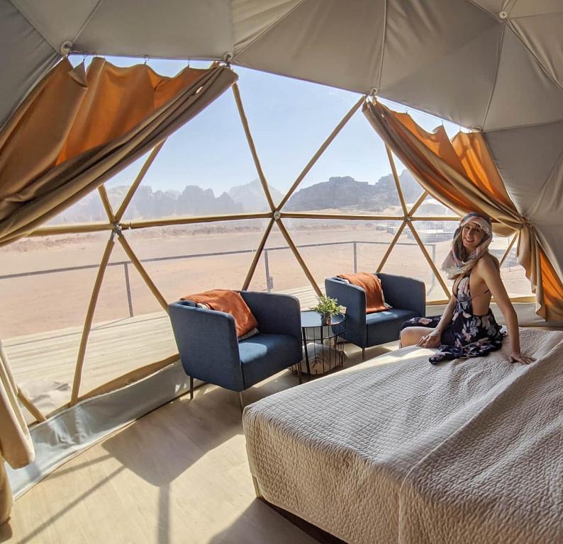 a woman sitting on a bed in a tent at Rum Leno Luxure camp in Wadi Rum