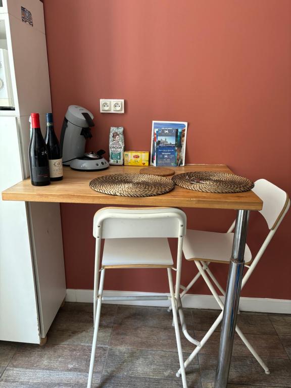- une table avec 2 chaises blanches et une table avec des bouteilles de vin dans l'établissement Studio saint Victor proche Vieux port, à Marseille