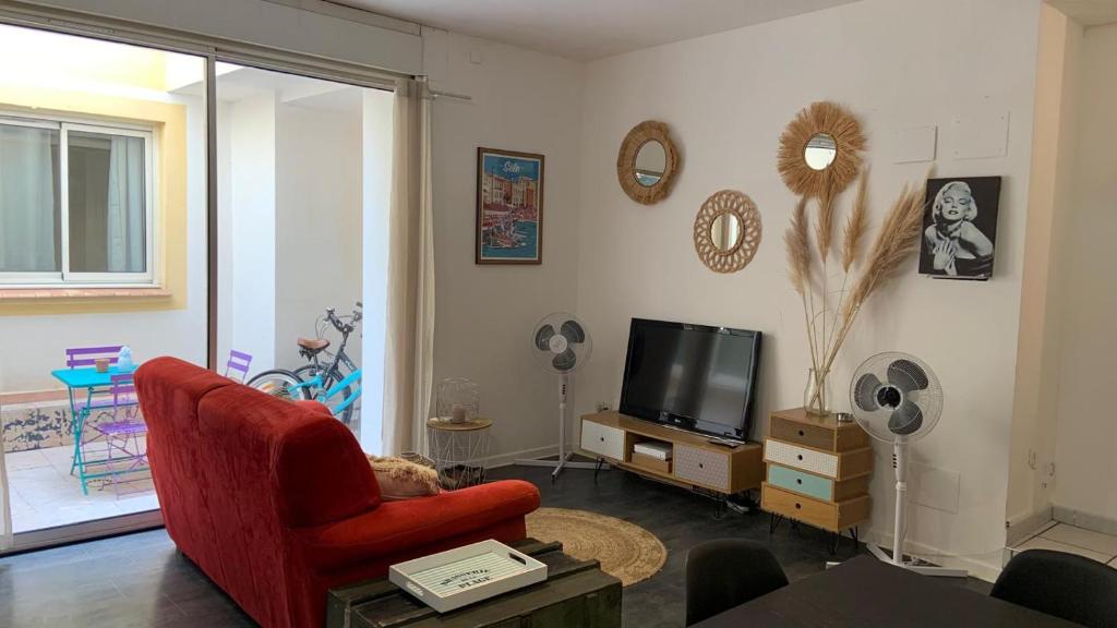 un salon avec une chaise rouge et une télé dans l'établissement Le patio, à Sète