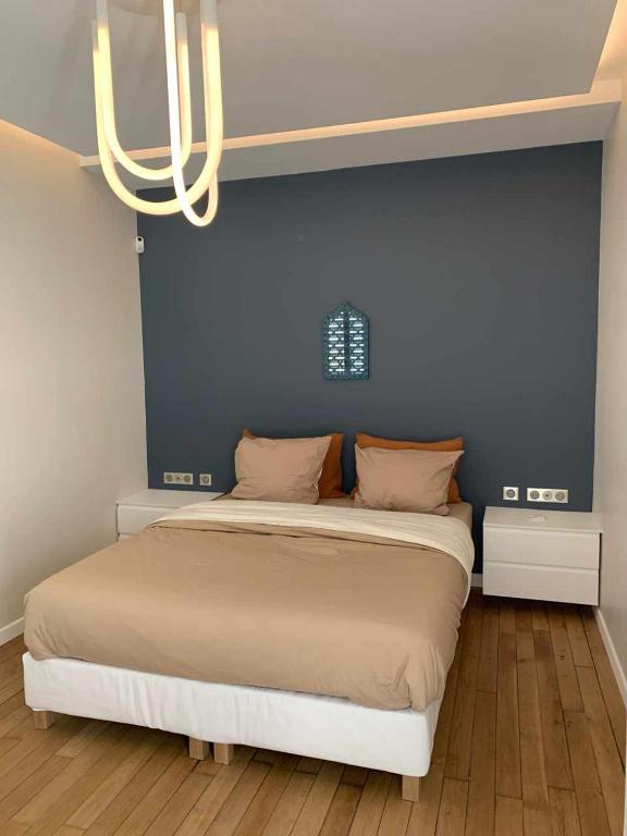 une chambre avec un lit avec un mur bleu dans l'établissement Studio confortable refait à neuf, à Saint-Ouen