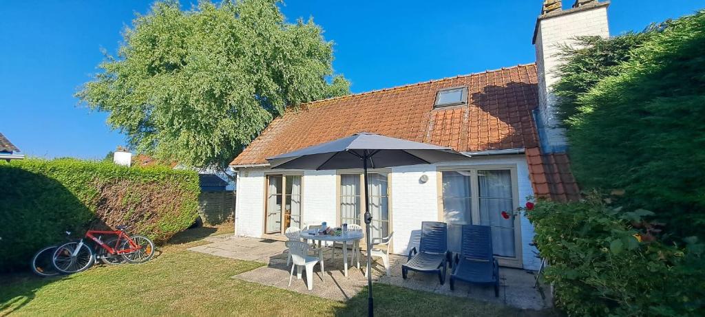 a house with a table and chairs and an umbrella at la maison de westende in Middelkerke