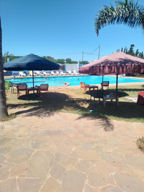 a group of tables and chairs next to a pool at Havre de paix à TAMARIS in Dar Mohammed Ould Haj Jilali