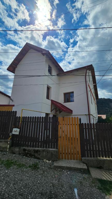 a white house with a fence in front of it at Vila Alma Azuga in Azuga