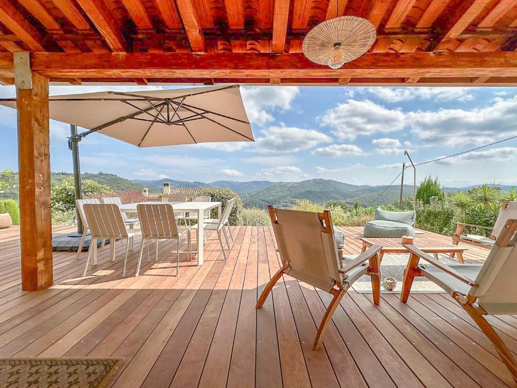 une terrasse en bois avec une table, des chaises et un parasol dans l'établissement Villa Le Soleil Bleu - Piscine - Jardin, à Le Tignet