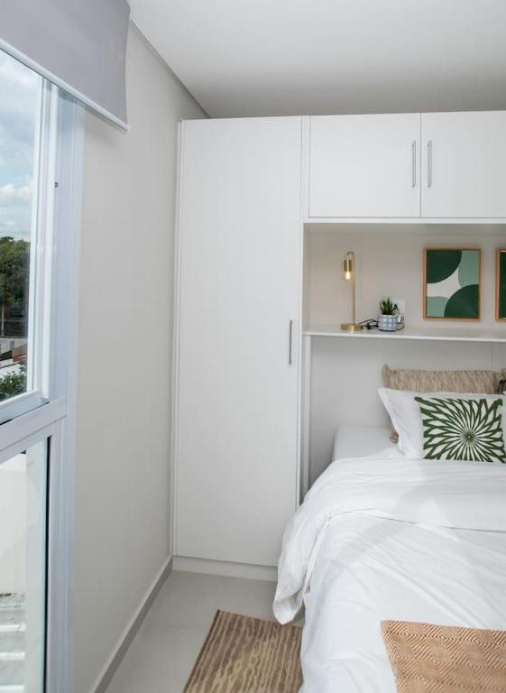 a white bedroom with a bed and a window at Stylish 2BR Apt in Top Location in Asunción