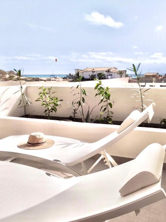 a white chair on a balcony with a hat at Stylish Lagoon Paradise Apartment Boa Vista in Sal Rei