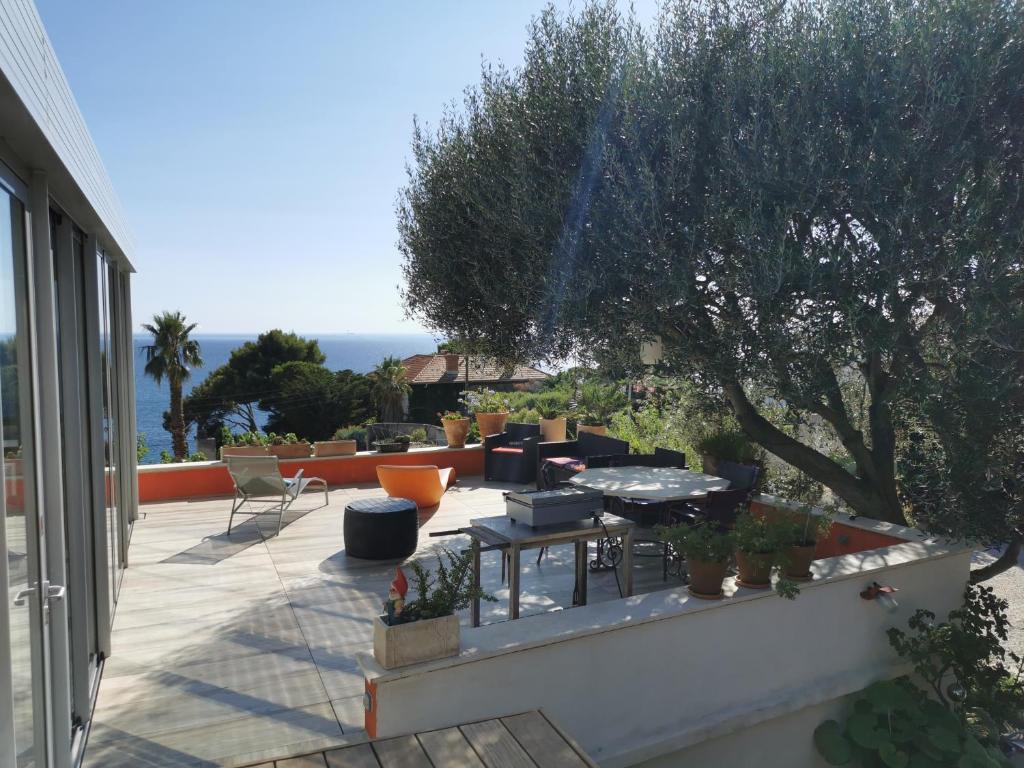 d'une terrasse avec une table, des chaises et un arbre. dans l'établissement VILLA HELIOS - vue mer, terrasse, jardin, piscine, parking, à Marseille