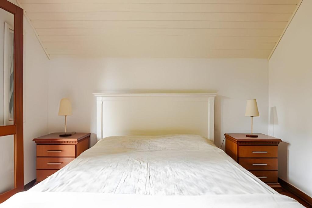 a bedroom with a large bed and two night stands at Apartamentos Centrinho Capivari - Recanto Boticário in Campos do Jordão