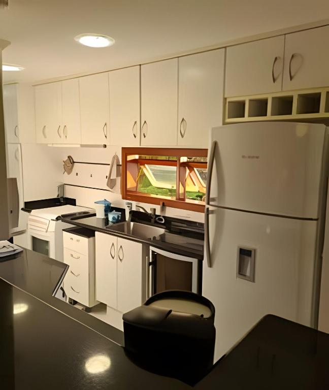 a kitchen with white cabinets and a refrigerator at Apartamentos Centrinho Capivari - Recanto Boticário in Campos do Jordão