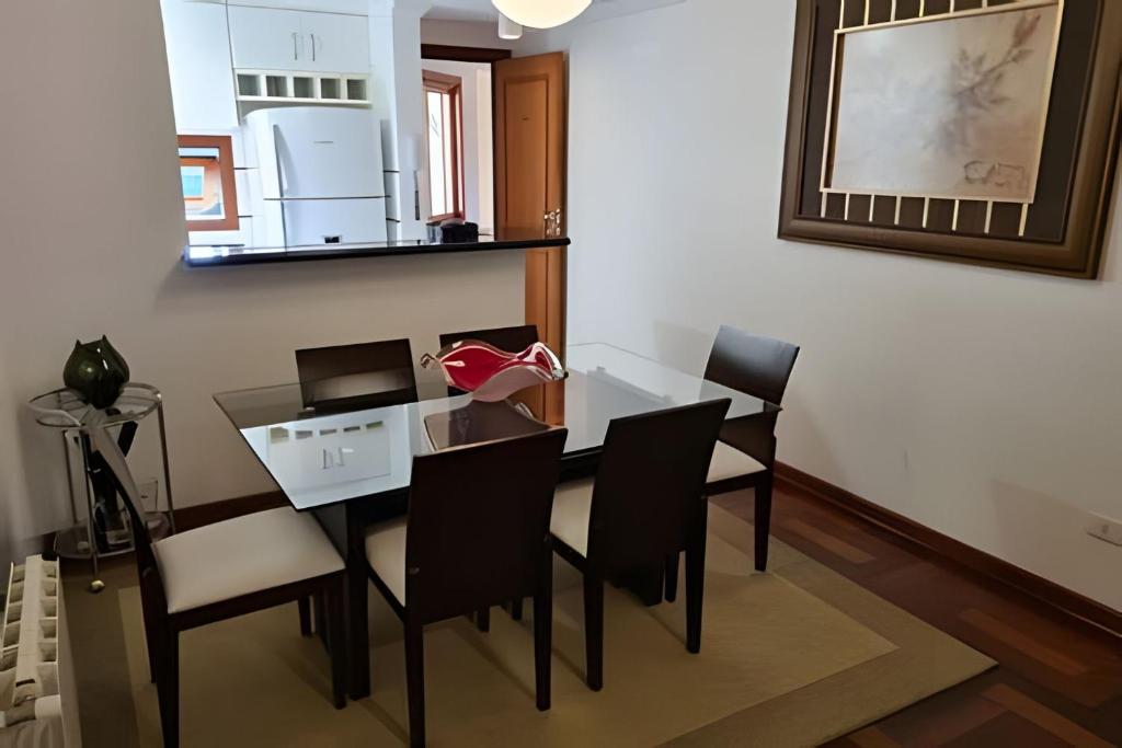 a dining room with a table and chairs and a refrigerator at Apartamentos Centrinho Capivari - Recanto Boticário in Campos do Jordão