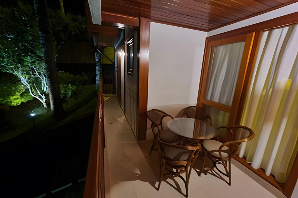 a room with a table and chairs on a balcony at Apartamentos Centrinho Capivari - Recanto Boticário in Campos do Jordão