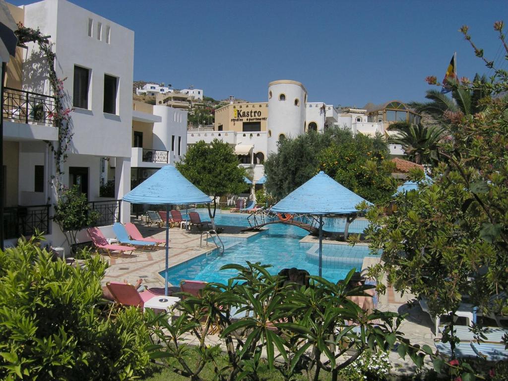 een zwembad met stoelen en parasols naast een gebouw bij Kastro Studios Apartments in Myrtos
