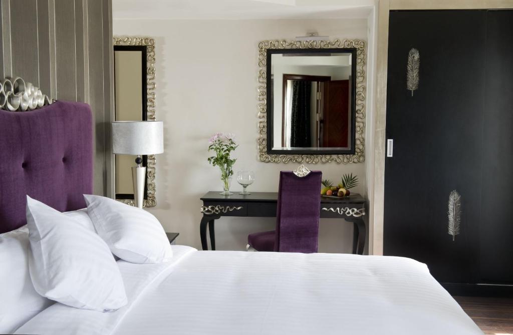 a bedroom with a large bed and a table with a mirror at Barceló Cairo Pyramids in Cairo