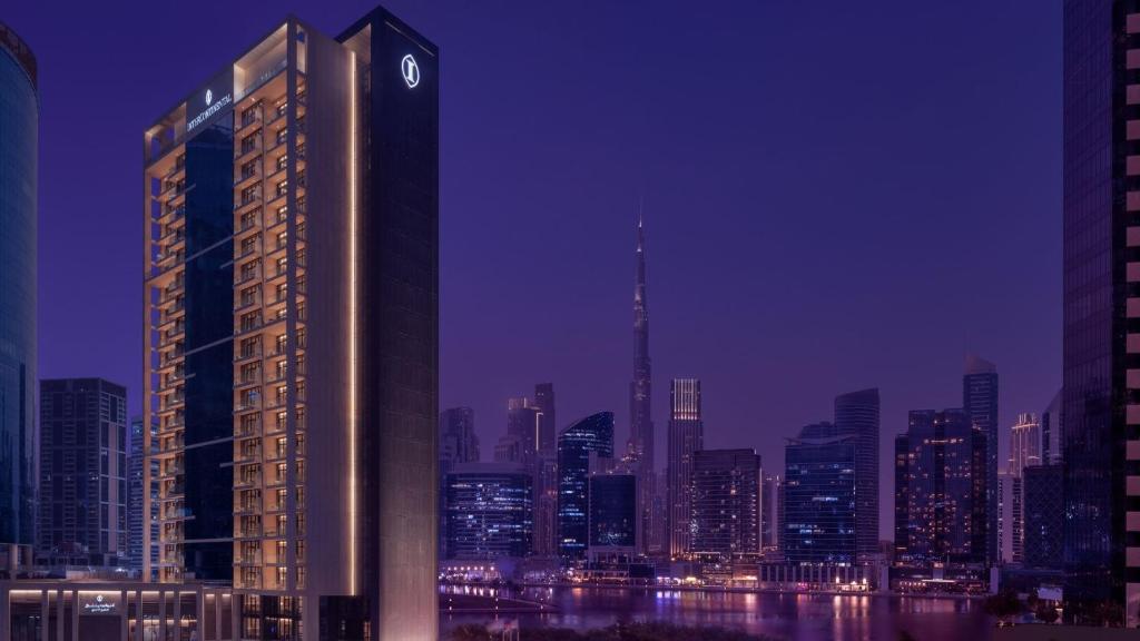 迪拜InterContinental Residences Dubai Business Bay by IHG的一座高大的建筑,在城市前面有钟