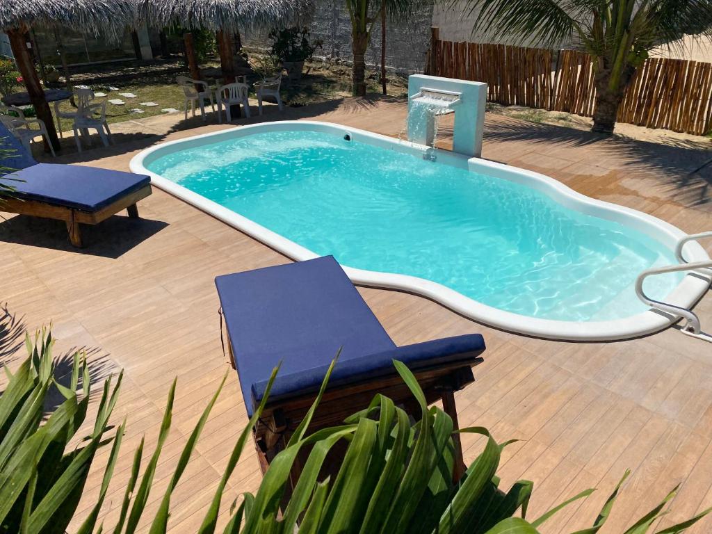 a pool with a bench and a chair in a yard at Casa Praia in Luis Correia