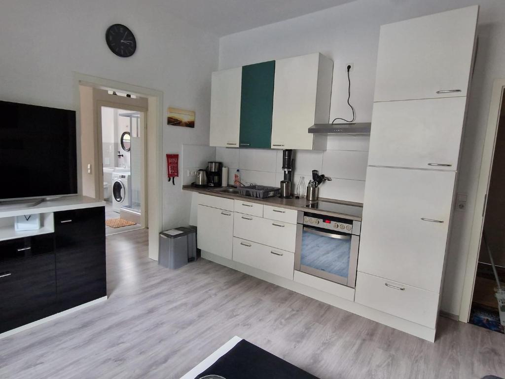 a kitchen with white cabinets and a flat screen tv at Ostwind in Bochum
