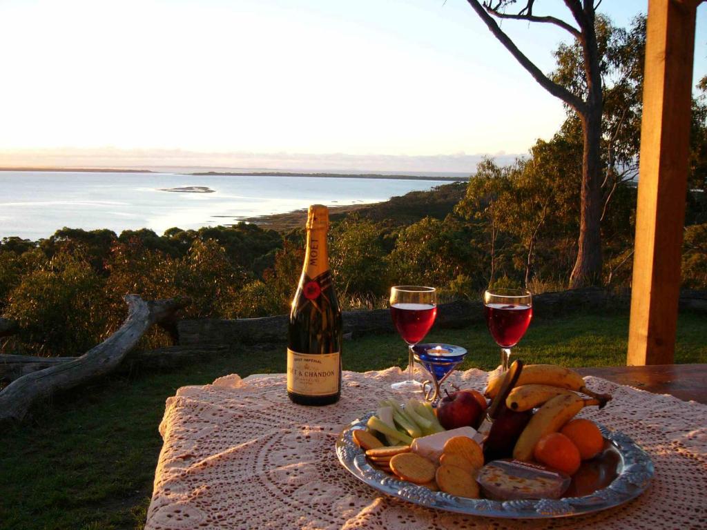 a table with a plate of food and a bottle of wine at Island View Spa Cottage in Smithton