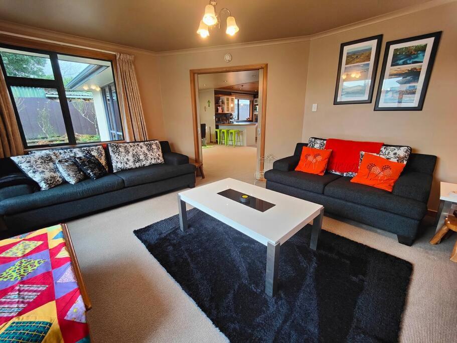 a living room with two couches and a table at A Haven in the Heart of the City in Invercargill