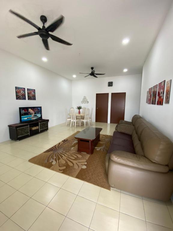 a living room with a couch and a ceiling fan at Ikhwan HOMESTAY CHERATING in Kampong Baharu