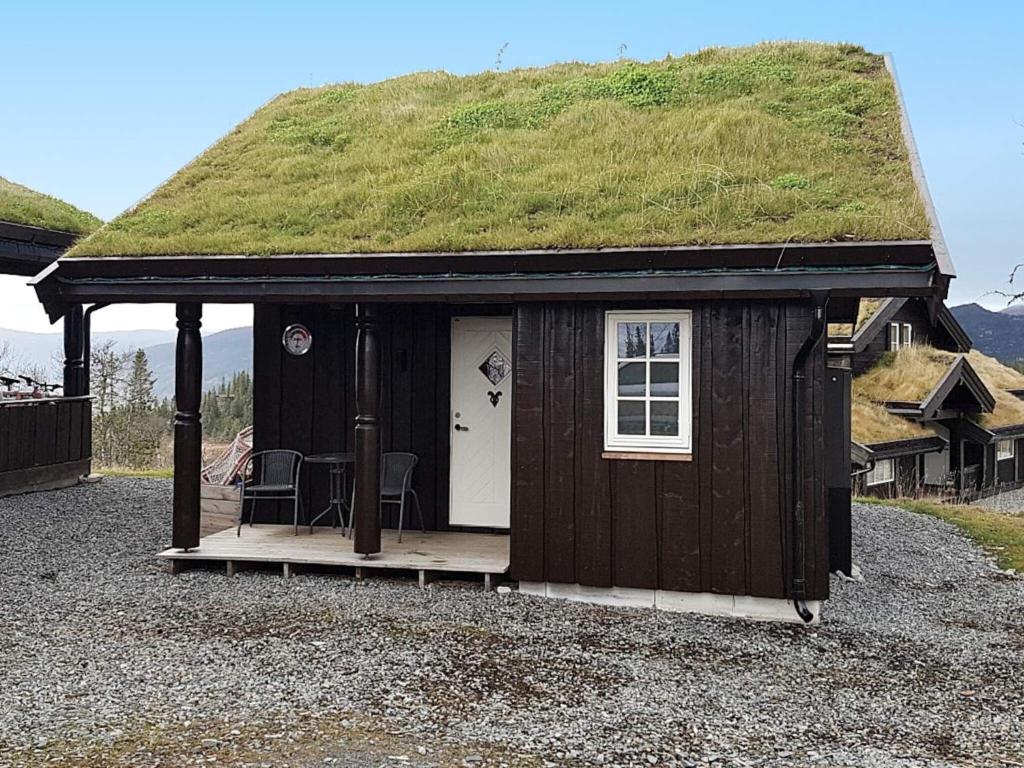 Una pequeña cabaña con techo de hierba y una mesa. en 4 person holiday home in EGGEDAL, en Eggedal