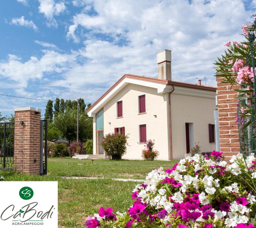 una casa bianca con dei fiori davanti di AgriCamping Ca' Bodi a Cavallino-Treporti