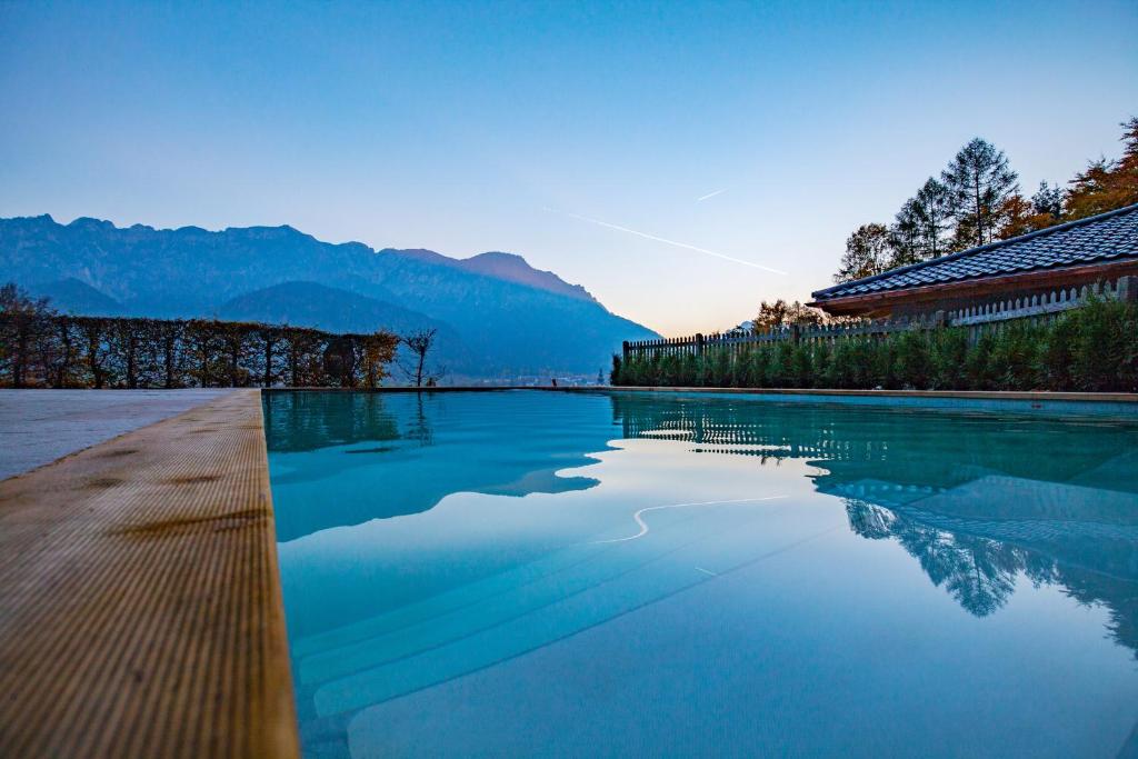 una piscina de agua con montañas en el fondo en Salzburg-Chalet, en Grossgmain