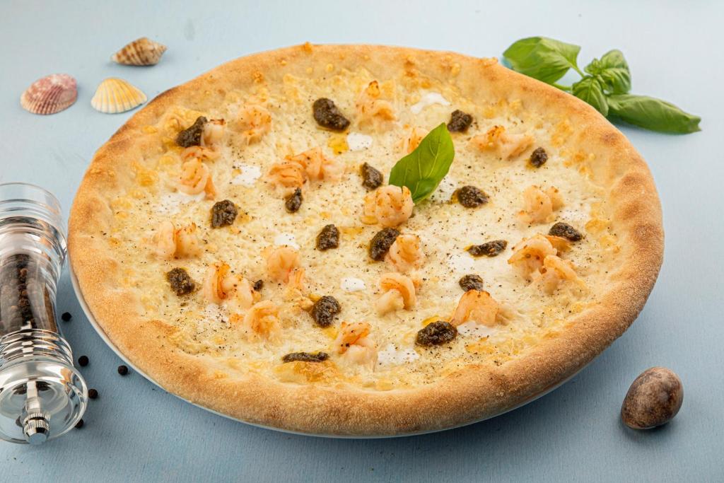 a pizza with shrimp on top of a table at Flamingo Beach Hotel in Umm Al Quwain