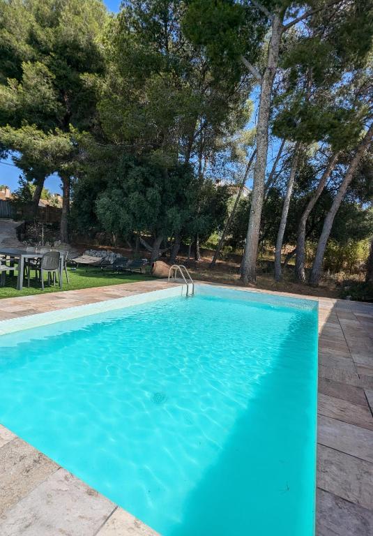 a large blue swimming pool in a yard with trees at Casa Martí in El Vendrell