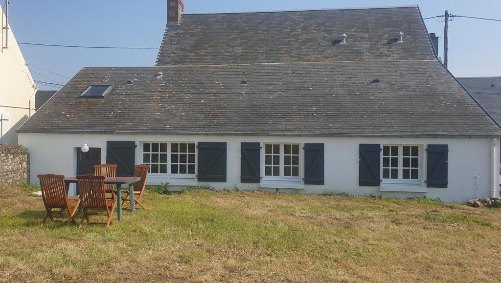une maison avec une table et des chaises devant dans l'établissement La maisonnette 2personnes le rdc à 1200m de la mer, à Agon-Coutainville