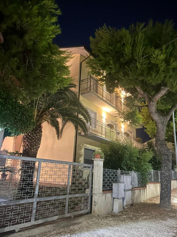 a building with a fence and two palm trees at Pensione Vagnozzi in Grottammare