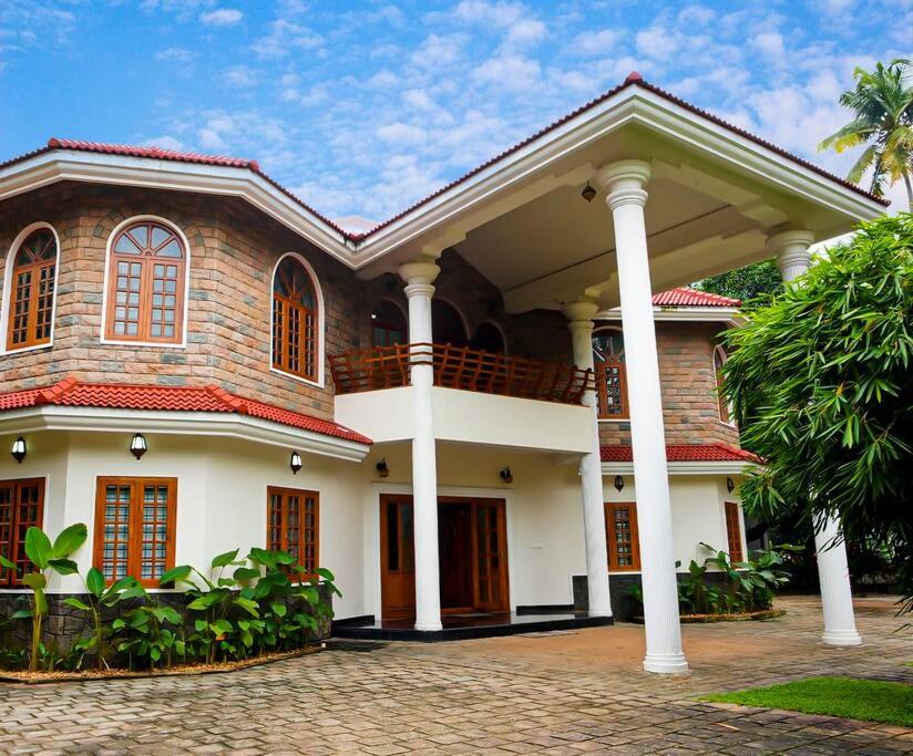 a large house with a porch and columns at Puzhayoram holiday home, Aluva in Alwaye