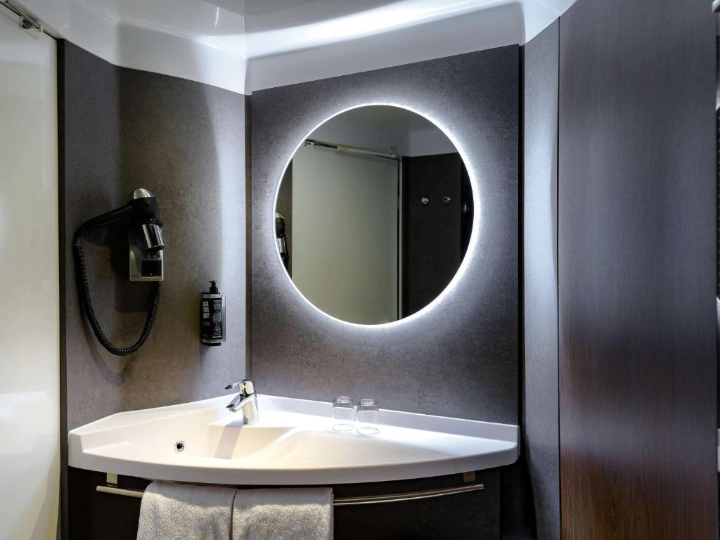 a bathroom with a sink and a mirror at ibis München Parkstadt Schwabing in Munich