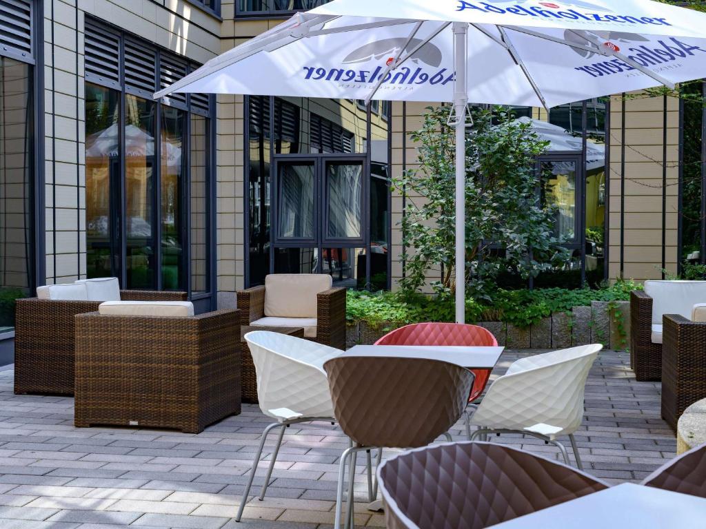 a table and chairs with an umbrella in front of a building at ibis München Parkstadt Schwabing in Munich