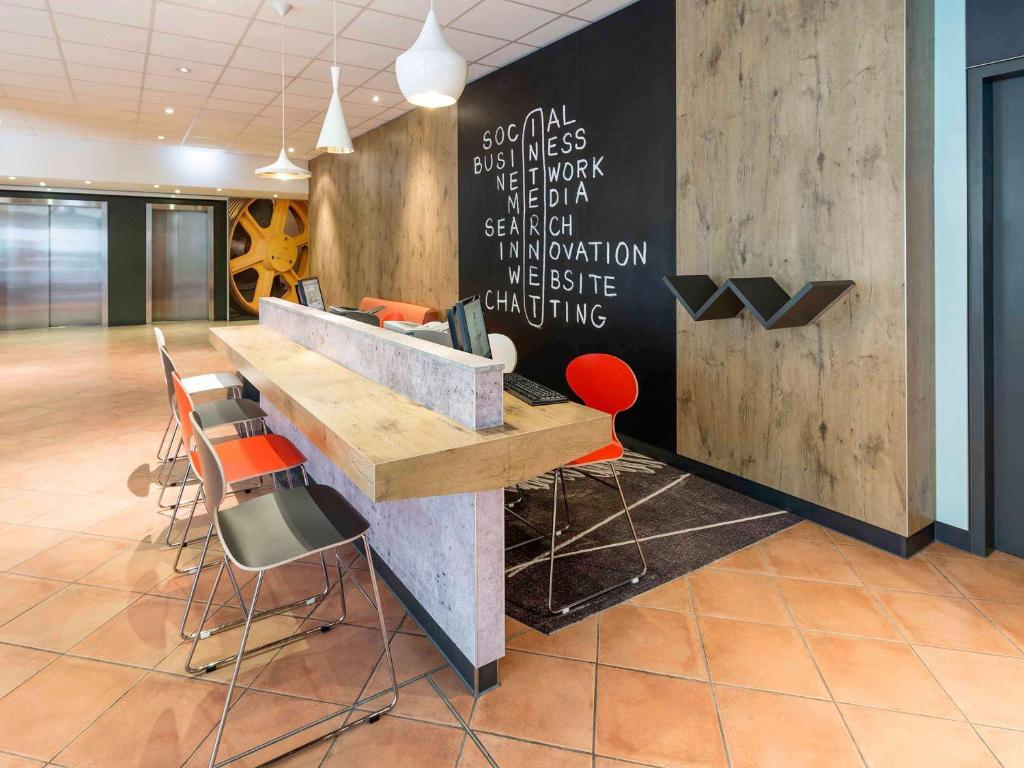a lobby with a desk and chairs in a room at ibis München Parkstadt Schwabing in Munich