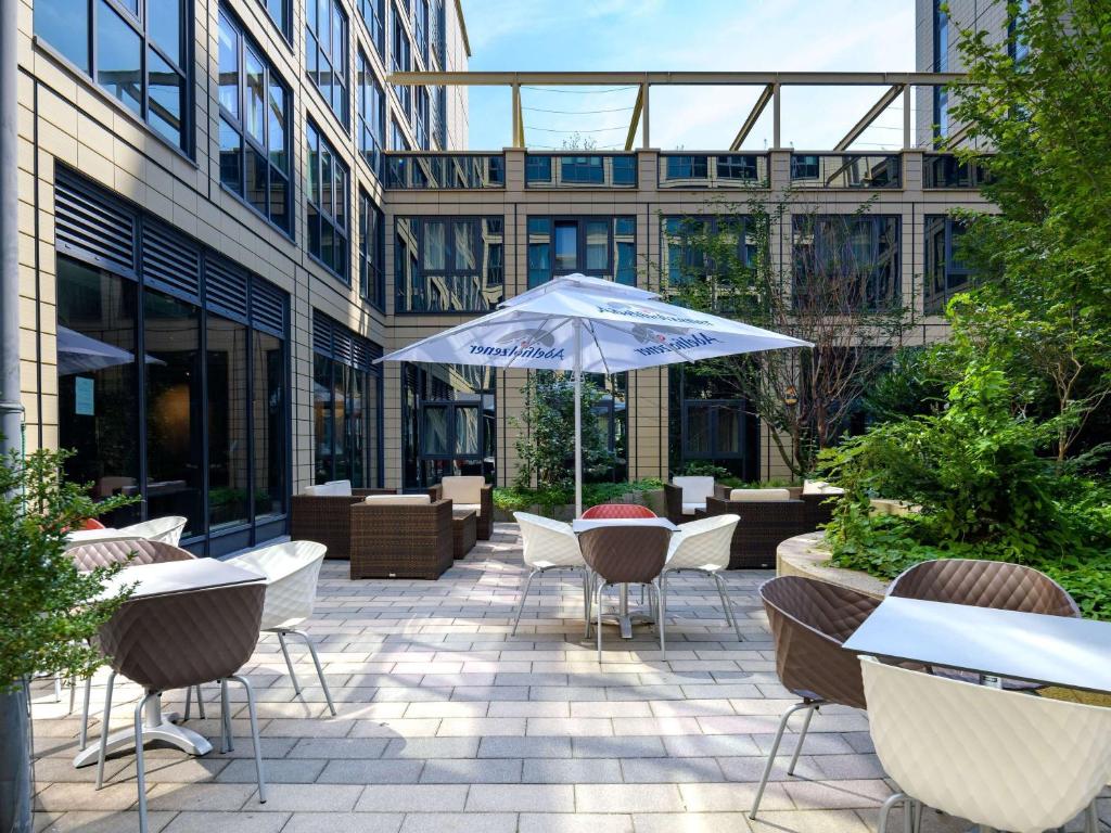 a patio with tables and chairs and an umbrella at ibis München Parkstadt Schwabing in Munich