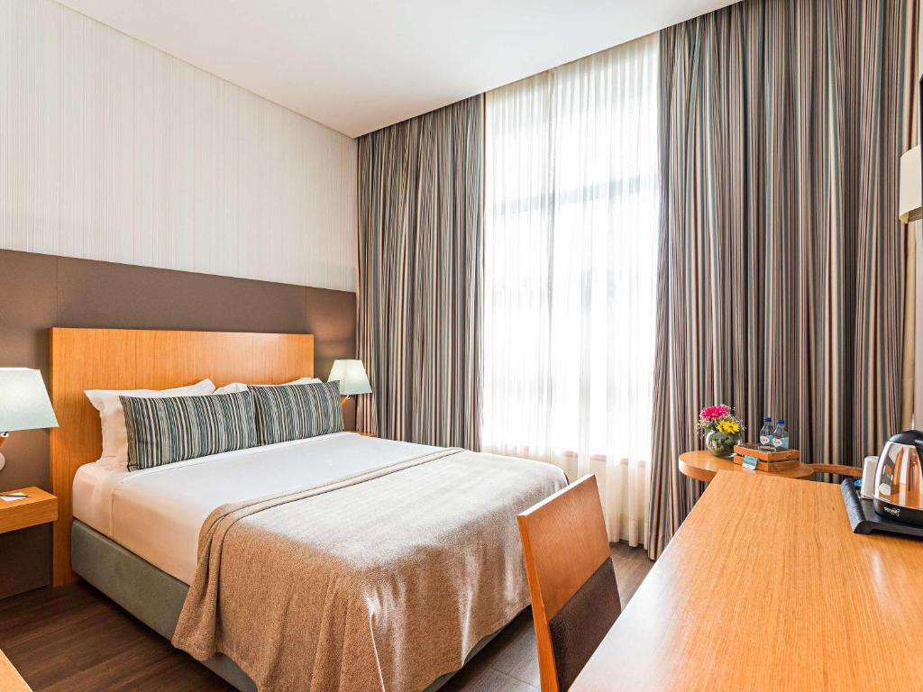 a hotel room with a bed and a window at Mercure Lisboa Almada in Almada