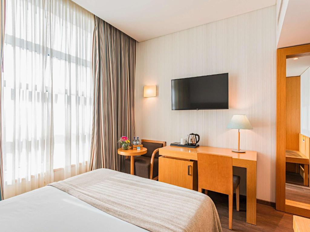 a hotel room with a bed and a desk at Mercure Lisboa Almada in Almada