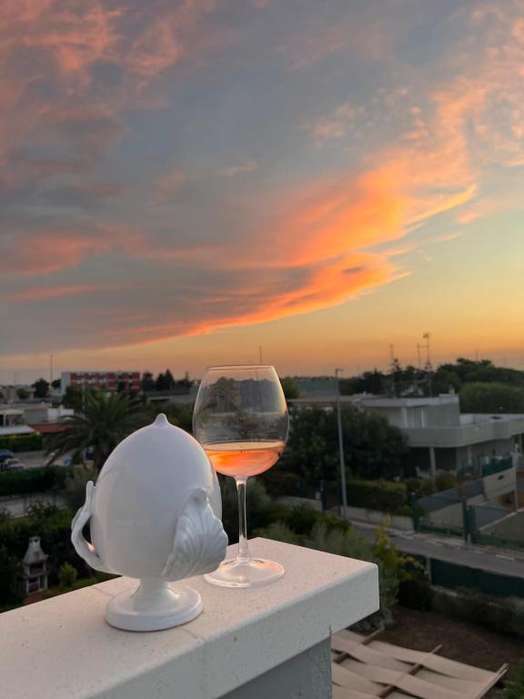 a glass of wine sitting on a ledge with the sunset at Marimar Apartment in Bari