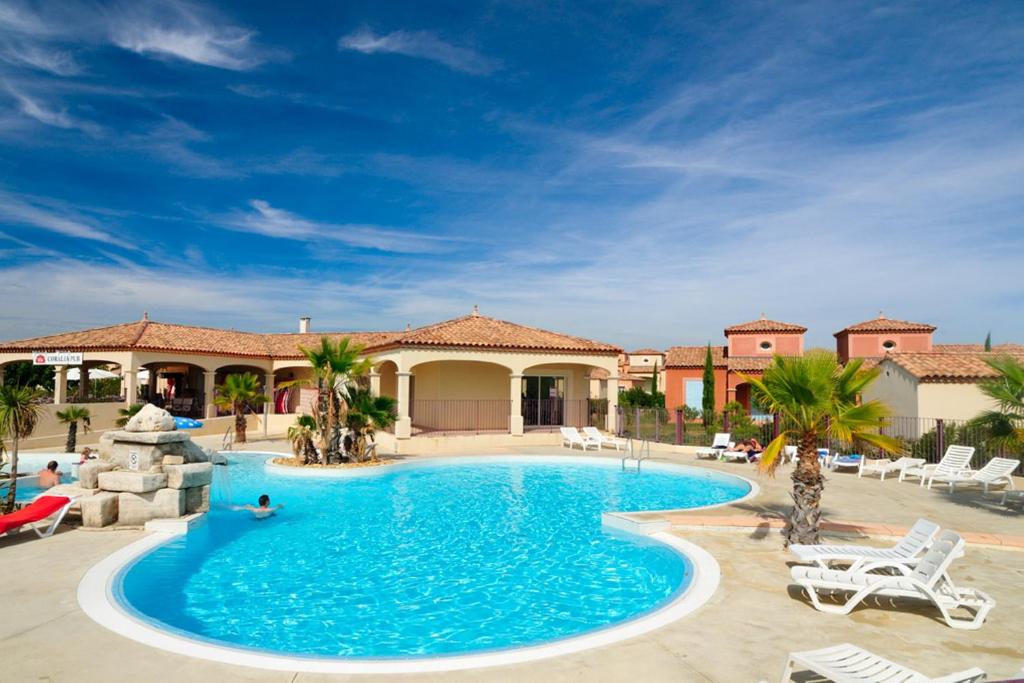 a large swimming pool in a resort with palm trees at Vacancéole - Port Minervois, Les Hauts du Lac in Homps