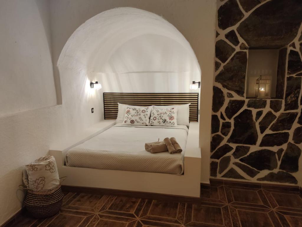 een slaapkamer met een bed met een stenen muur bij Casa Cueva Ca Maruca in Gáldar