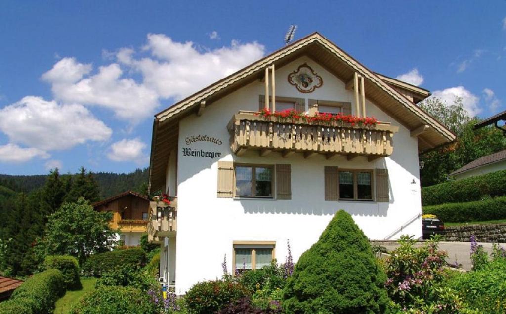 ein weißes Haus mit einem Balkon mit Blumen darauf in der Unterkunft Ferienwohnung Am Blumengarten in Bodenmais