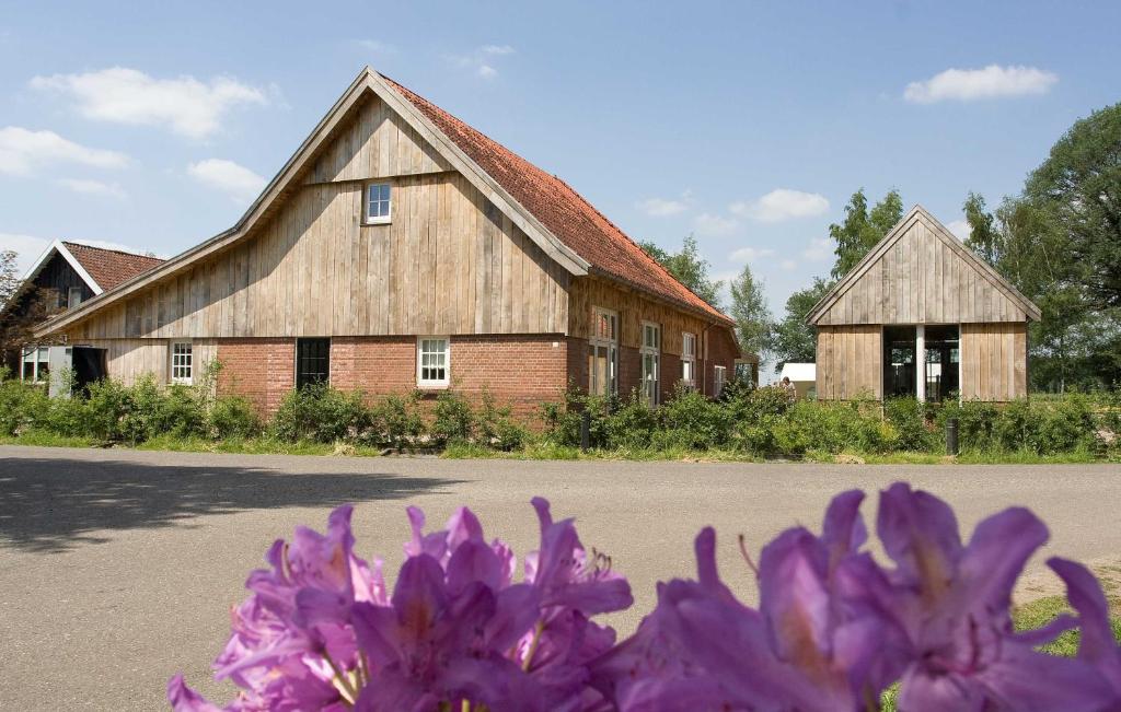 a large barn with purple flowers in front of it at Erve Fakkert in Rossum