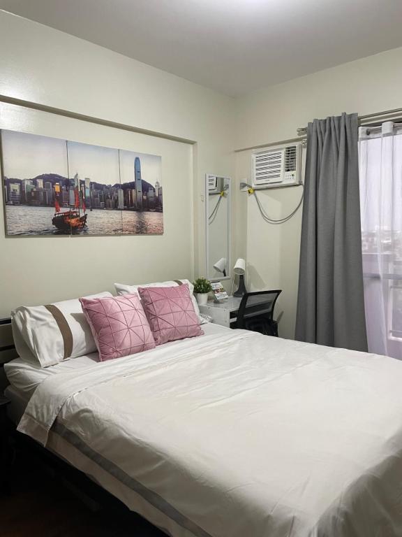 a bedroom with a large white bed with pink pillows at Eves Urban Haven in Manila